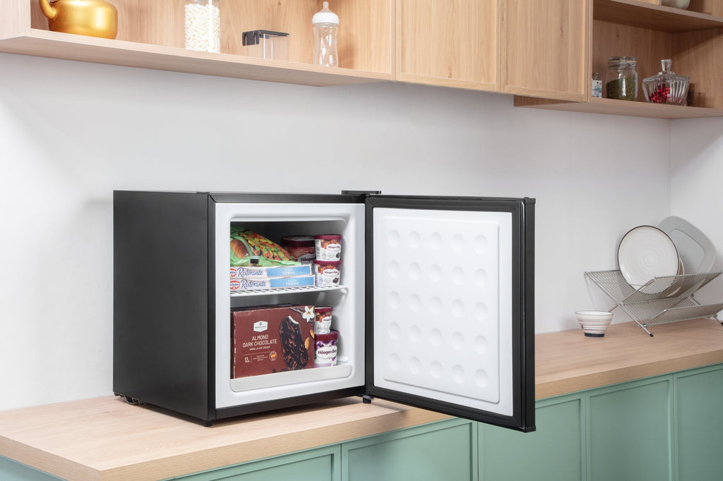 Black mini freezer with open door on a cabinet counter, stocked shelves inside