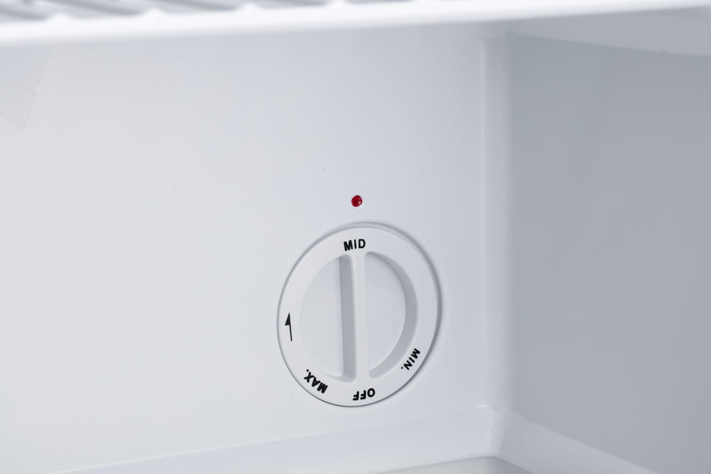 Mini freezer temperature control dial on white interior wall