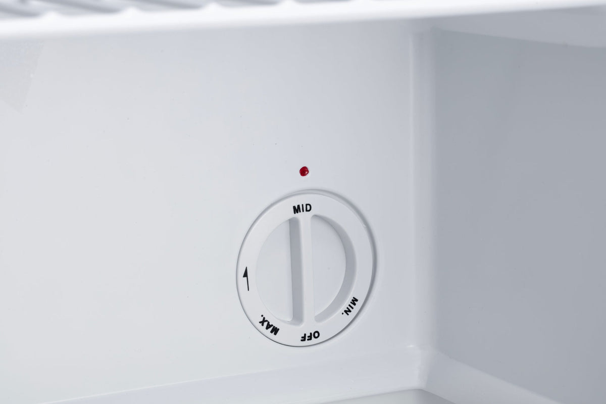 Mini freezer temperature control dial on white interior wall