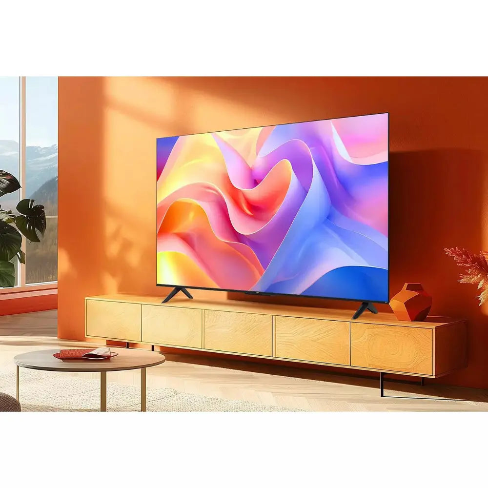 TCL 55-inch LED TV on stand with colorful abstract display and slim bezel