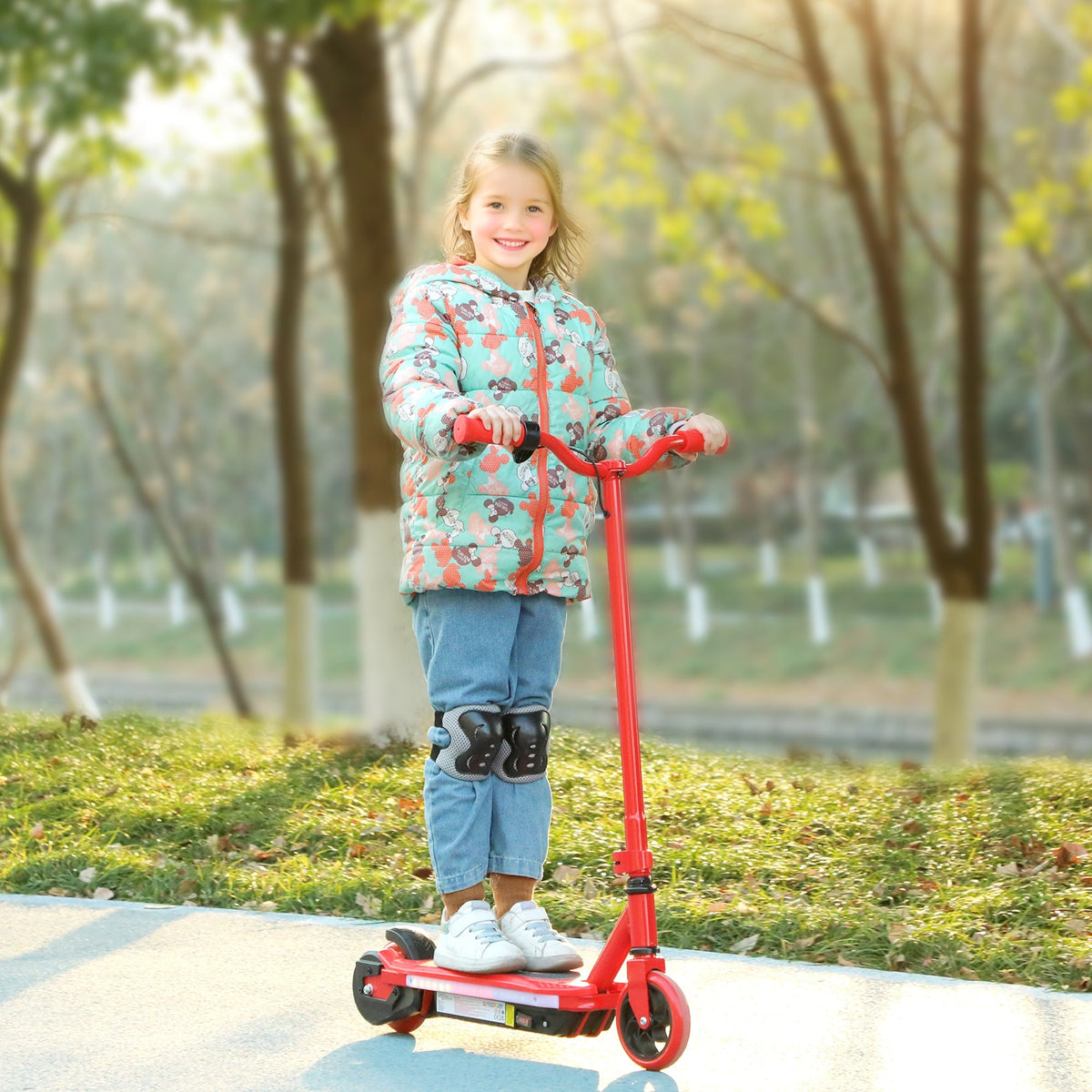 Red electric scooter with child standing on deck and holding handlebars