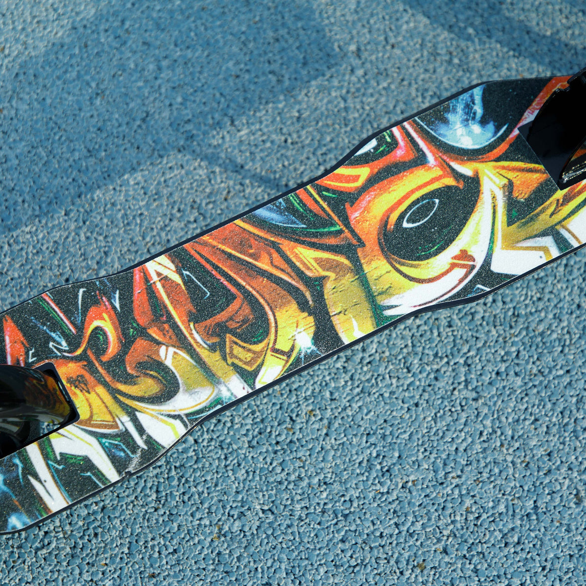 Close-up of colorful graffiti-style deck on a black kids kick scooter