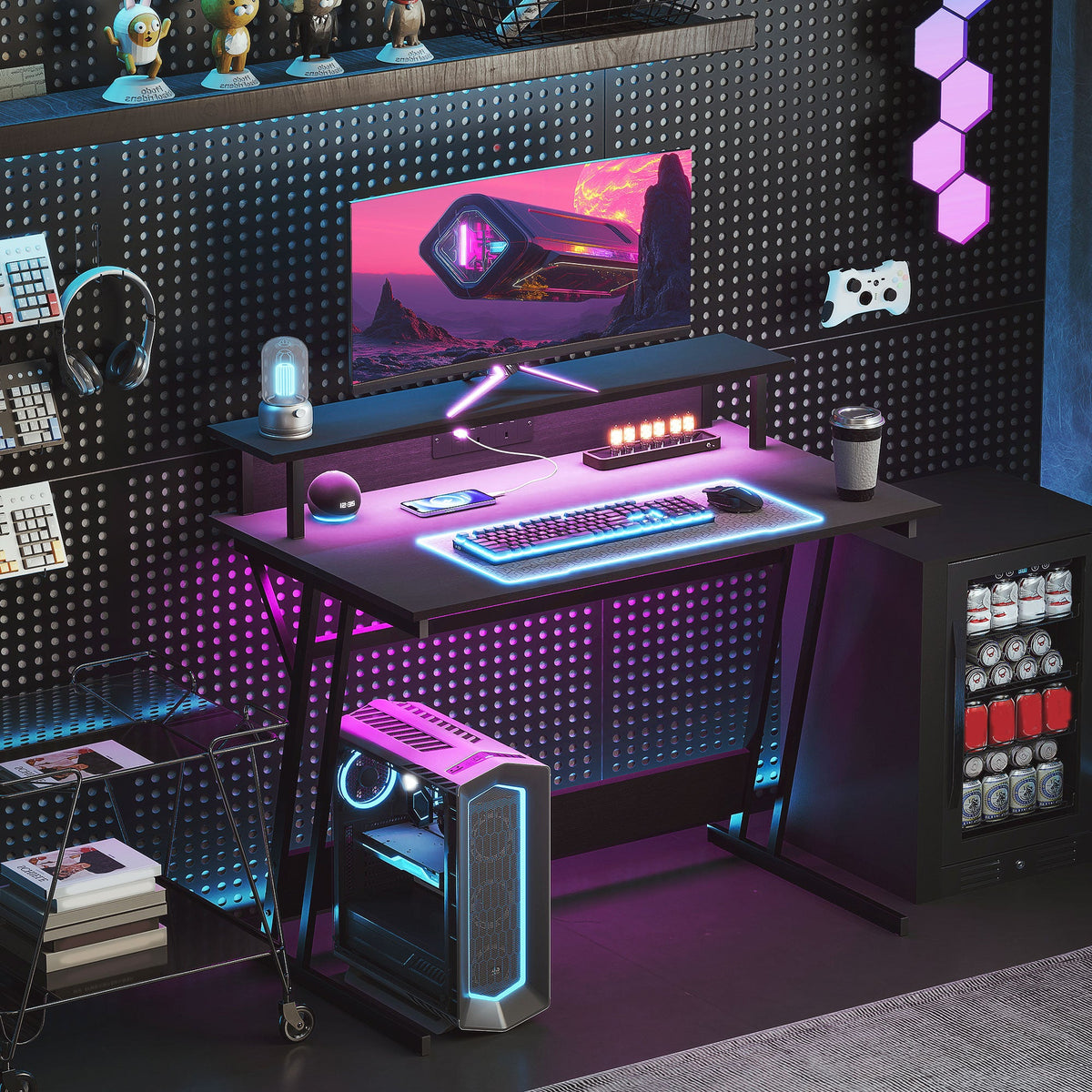 Black gaming desk with RGB LED lighting, monitor stand, and keyboard tray