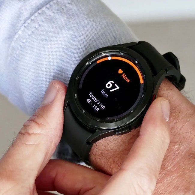 Black smartwatch on wrist showing fitness screen, round bezel and silicone strap