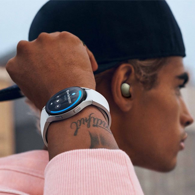 Smartwatch with white band on wrist, blue-lit bezel and dark watch screen