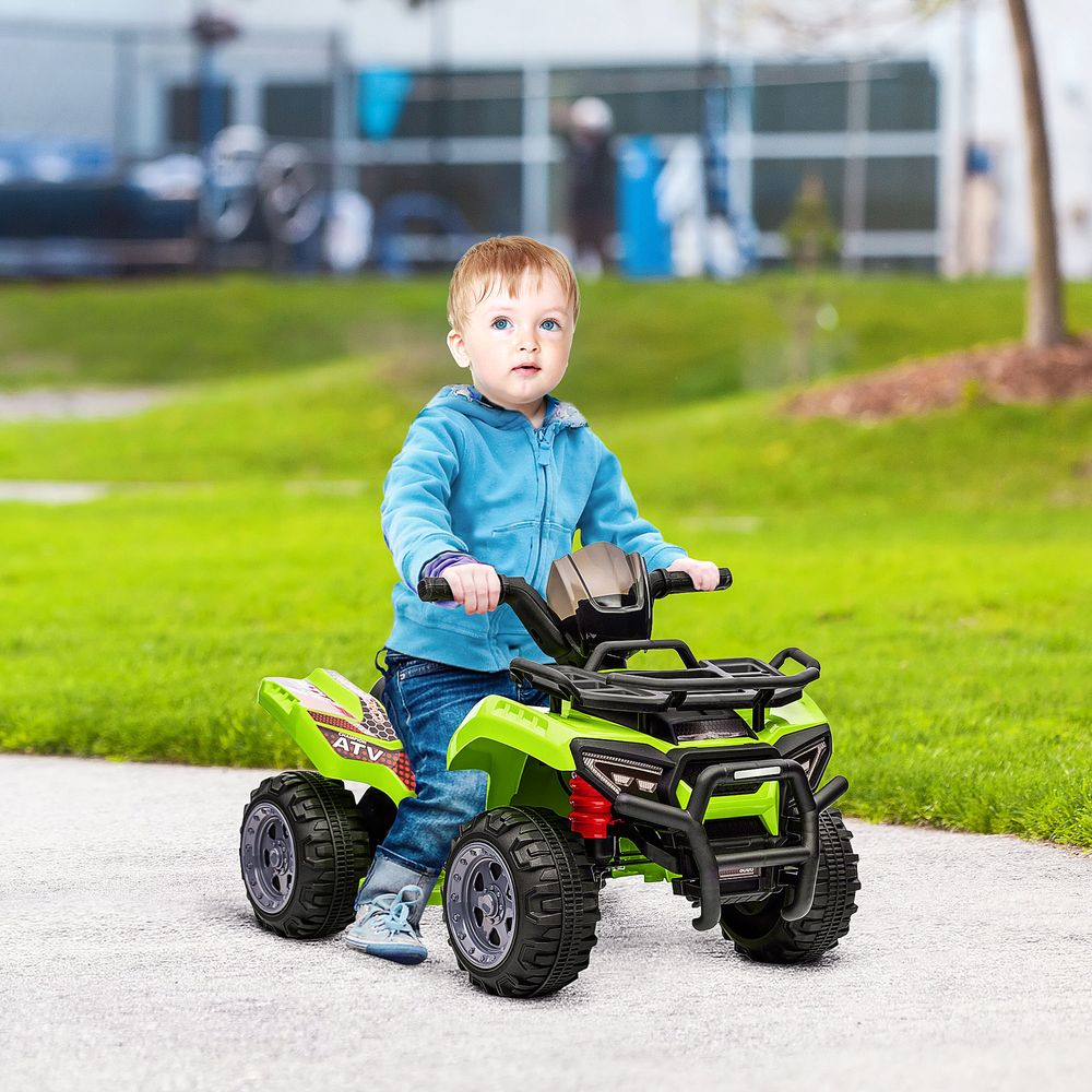 Child riding a lime green electric quad bike with black roll cage