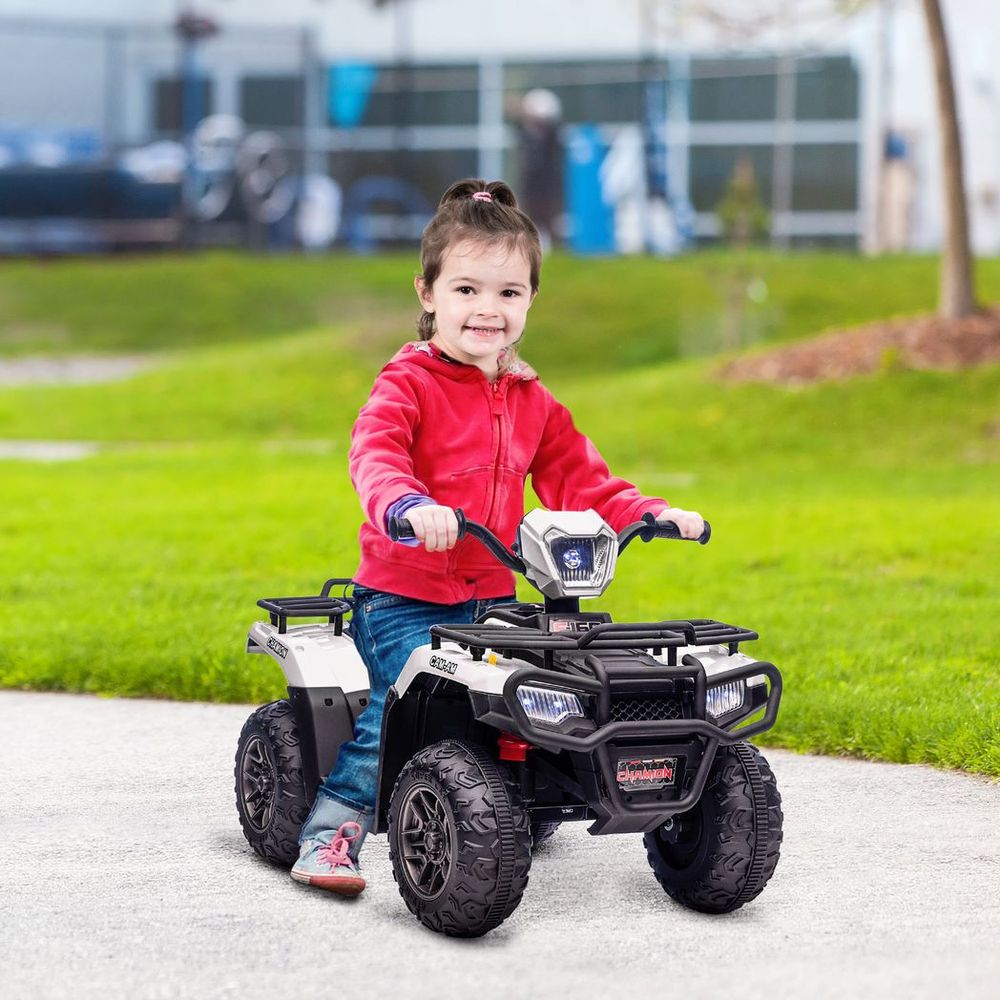 Child riding a white kids electric quad bike with LED front lights outdoors