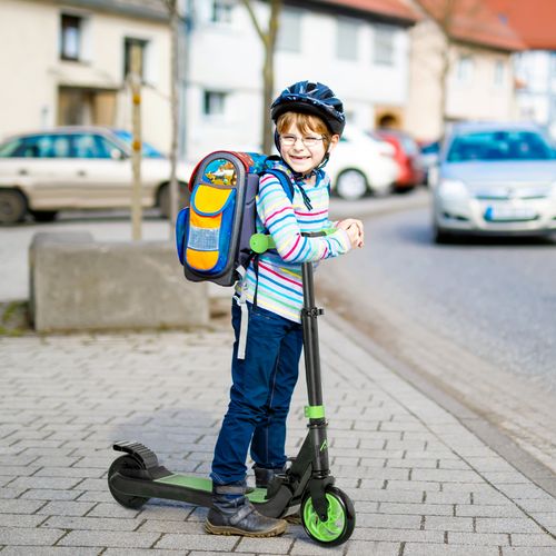Green and black folding electric scooter with child standing on the deck