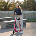 Pink foldable electric scooter with black seat and deck, upright with front wheel visible