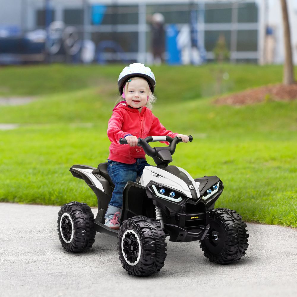 Child riding a white and black kids electric quad bike with LED headlights and four tires