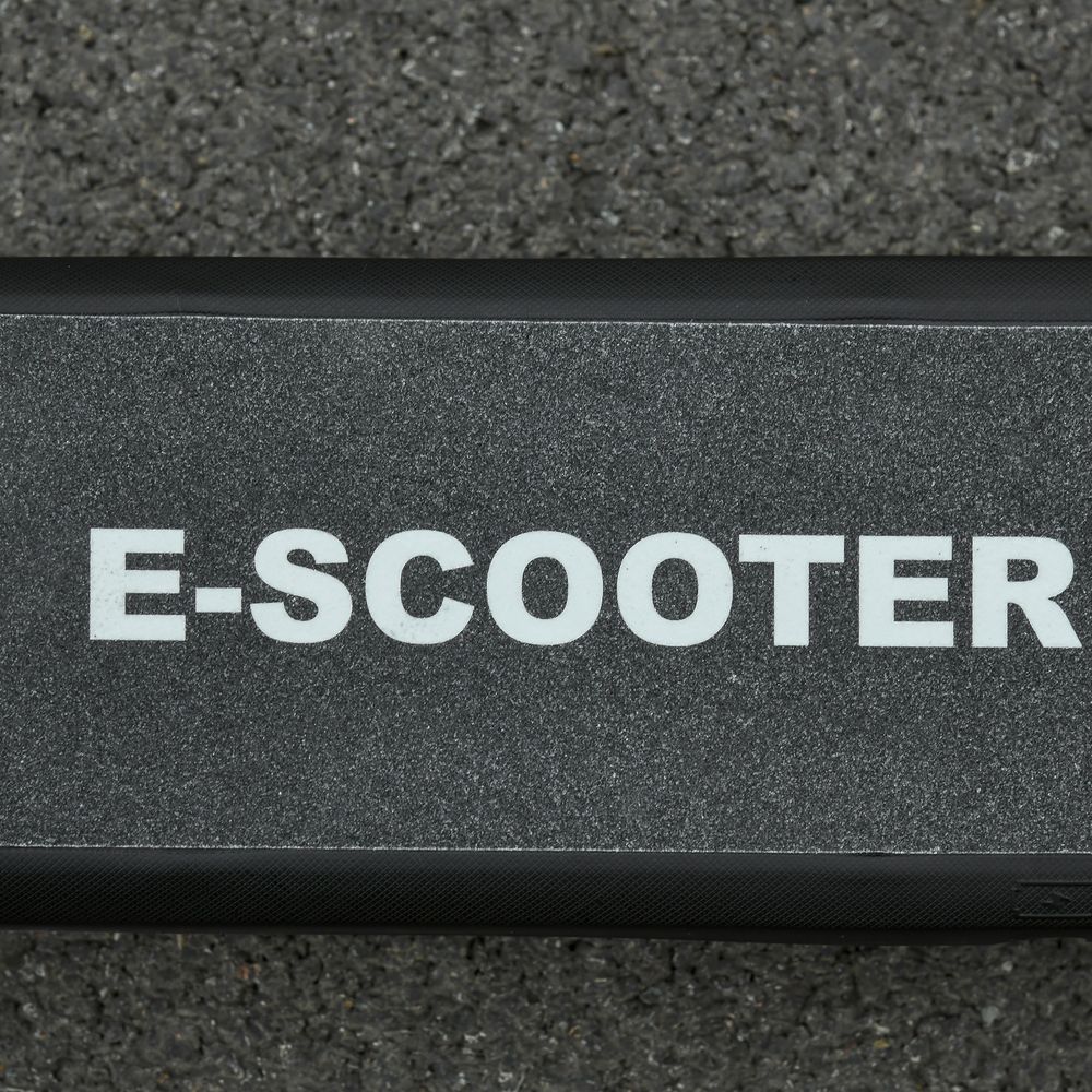 Black electric scooter deck with “E-SCOOTER” text label