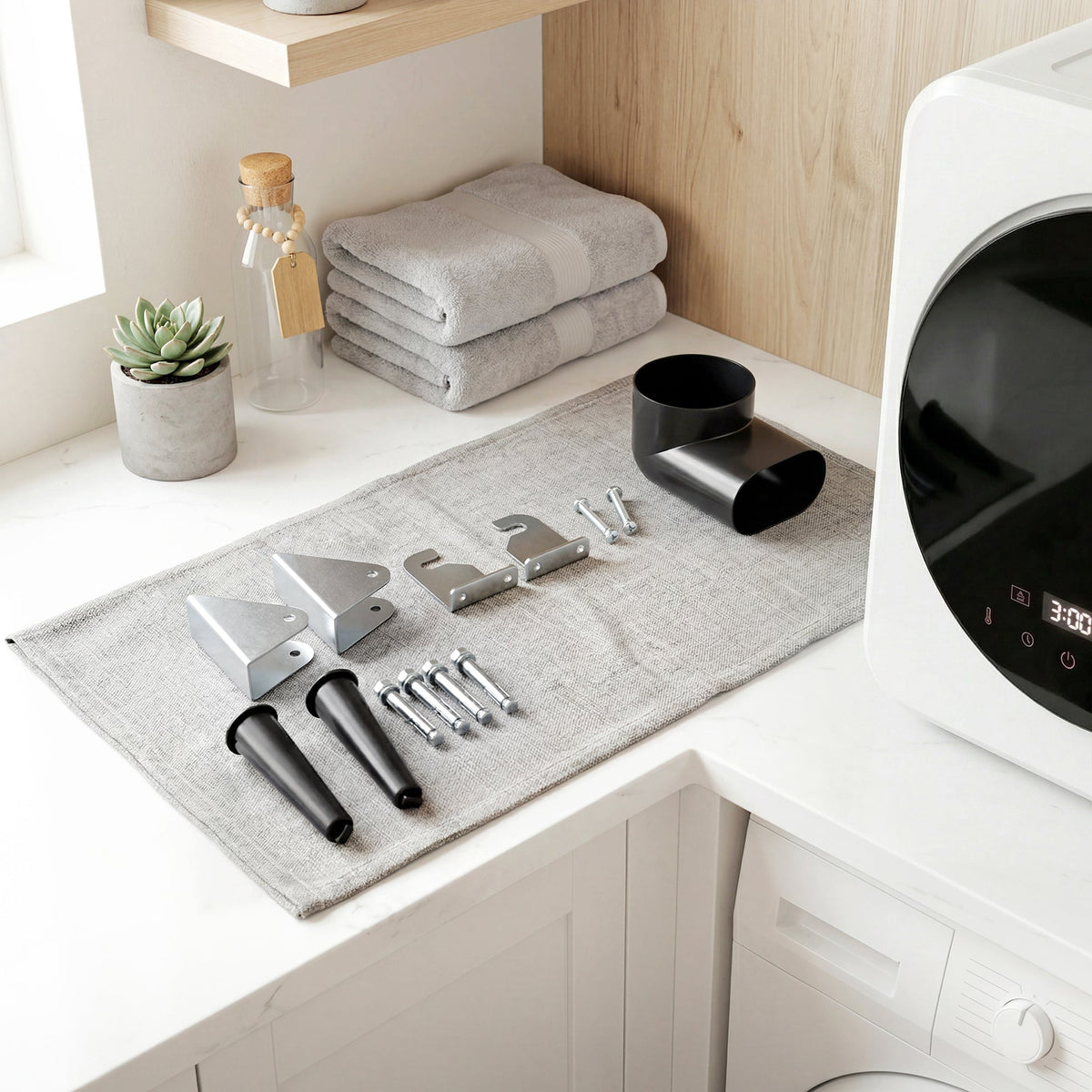 White wall-mounting kit parts laid out beside a compact tumble dryer