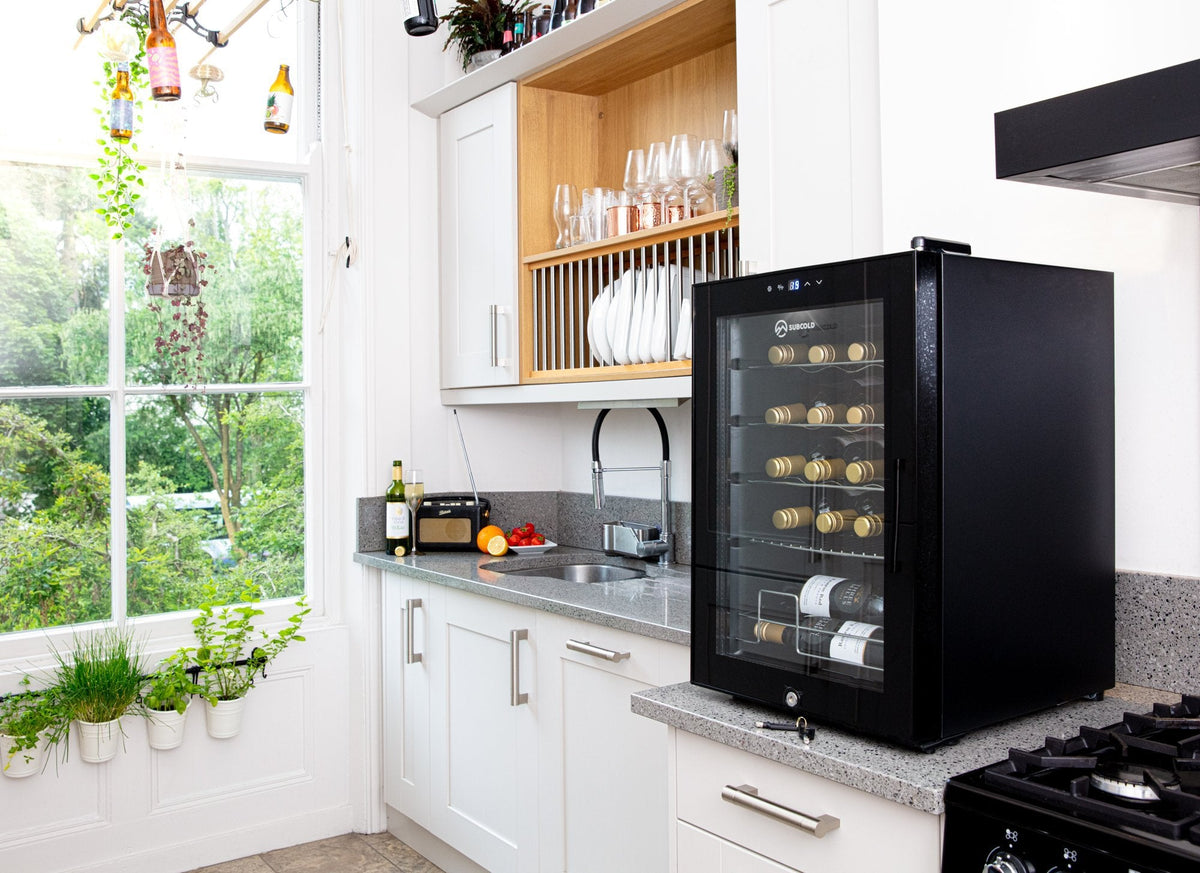 Black countertop wine cooler with open glass door and shelves